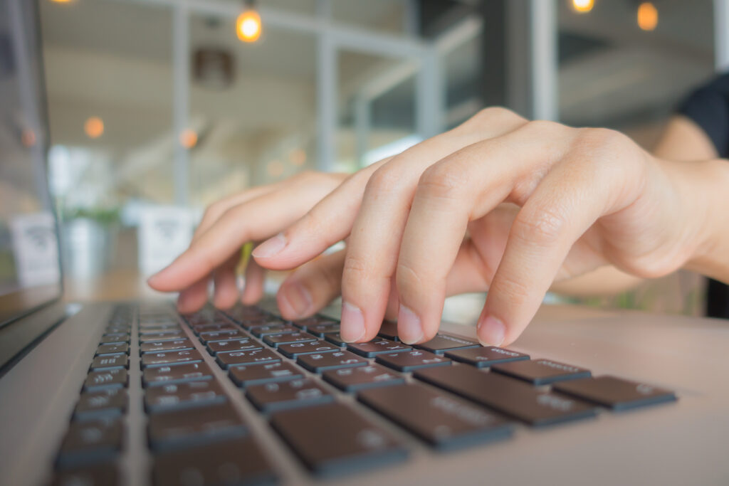 Closeup of business woman hand typing on laptop keyboard